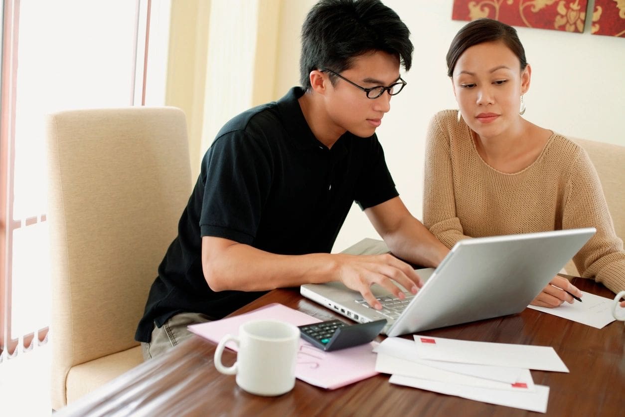 A man and woman are looking at a laptop.