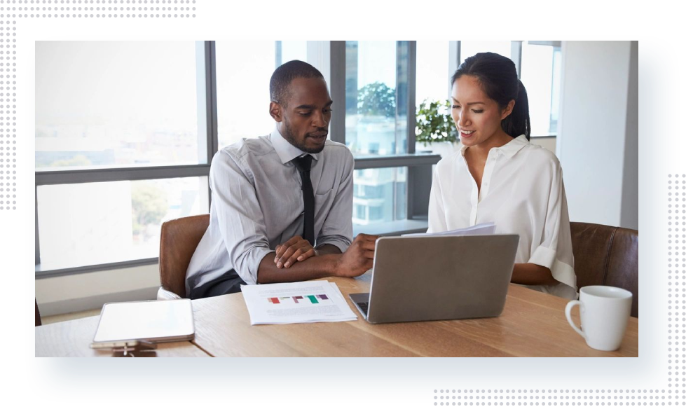 Two people sitting at a table with a laptop